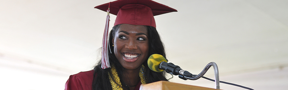 Student stands at podium on graduation day with a big smile